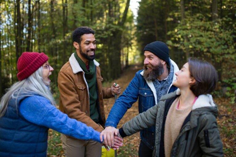 Four people in the forest put their hands in for a high 5